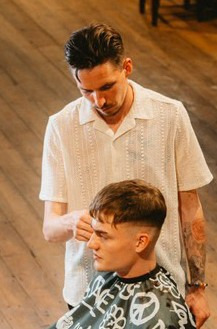 Barber expertly uses Olivia Garden Jean tools on customer in a stylish barbershop, embodying precision and high-quality standards.