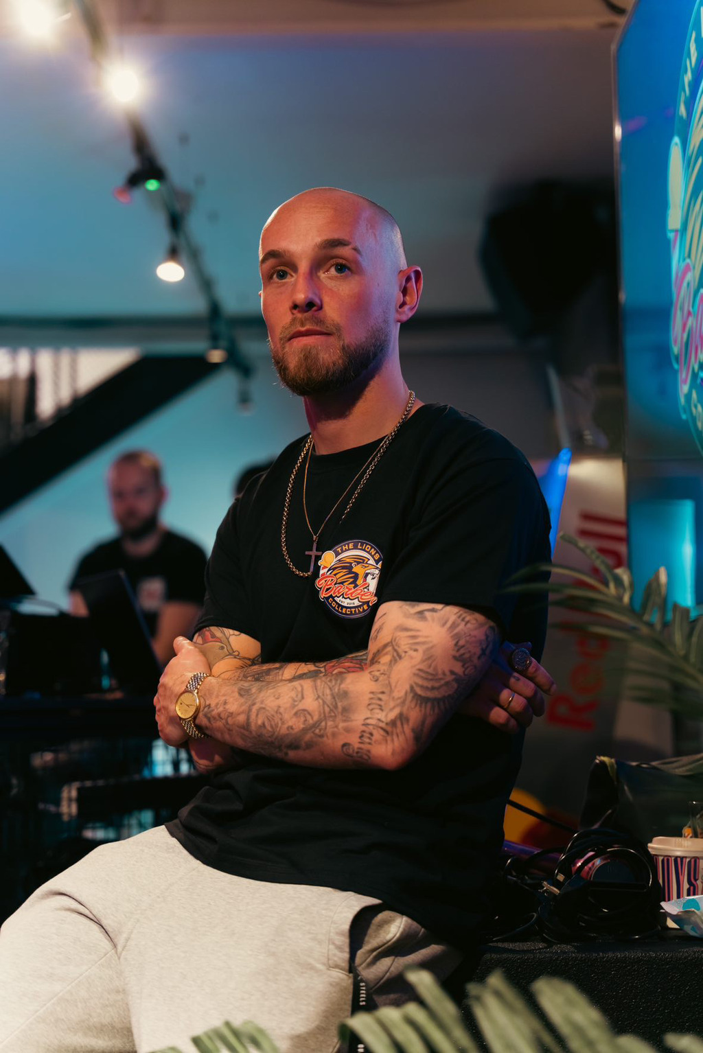 Tattooed, bearded man models Olivia Gardens dedication to high-quality tools, wearing a branded tee in a stylish studio setting.